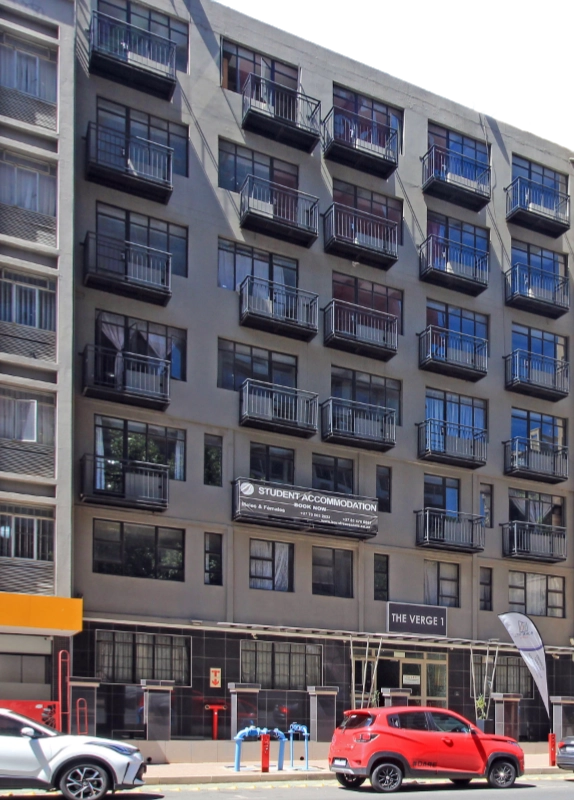 A multi-story modern building in Braamfontein with numerous windows and balconies, featuring a sign that reads "Born Free Student Accommodation."